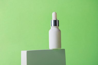 Krem veya losyon için plastik beyaz tüp. Yeşil arka planda şık dekorları olan cilt bakımı veya güneş kremi kozmetiği.