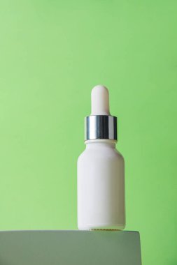 Krem veya losyon için plastik beyaz tüp. Yeşil arka planda şık dekorları olan cilt bakımı veya güneş kremi kozmetiği.