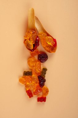 Tahta kaşıkta çeşitli renkli jelibonlar. Üst Manzara. Jöleli çörekler. Jelibon. krema arkaplanı.