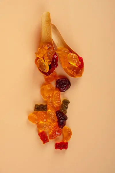 Tahta kaşıkta çeşitli renkli jelibonlar. Üst Manzara. Jöleli çörekler. Jelibon. krema arkaplanı.