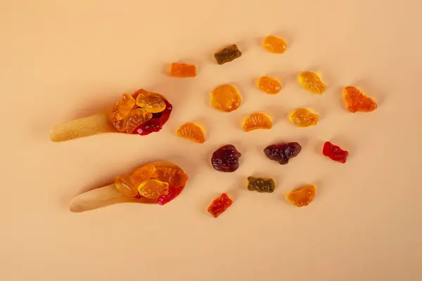 Tahta kaşıkta çeşitli renkli jelibonlar. Üst Manzara. Jöleli çörekler. Jelibon. krema arkaplanı.