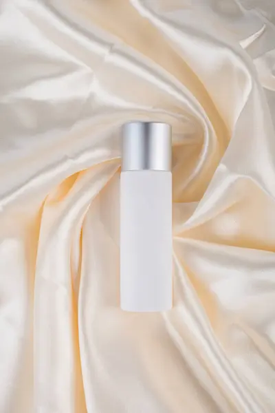 Kozmetik ürünler tüp, şişe, losyon ya da serumda parlak kumaş arka planında