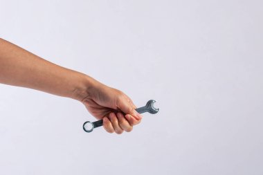 Beyaz arka plan üzerinde izole bir İngiliz anahtarı tutan el.