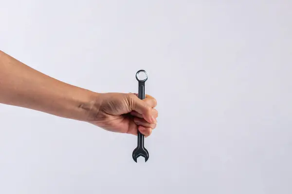 Beyaz arka plan üzerinde izole bir İngiliz anahtarı tutan el.