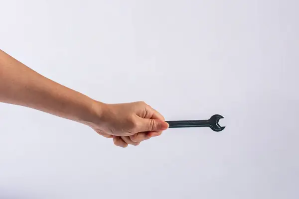 Beyaz arka plan üzerinde izole bir İngiliz anahtarı tutan el.