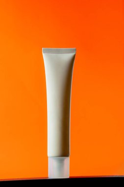  Turuncu arka planda nemlendirmek için kozmetik ürünü içeren boş bir tüp.