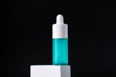 Mavi cam kozmetik şişesi, cilt bakımı ya da siyah arka planda şık dekorları olan güneş kremi kozmetik ürünleri..