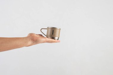 Eldeki paslanmaz çelik bardak beyaz arka planda izole edilmiş.