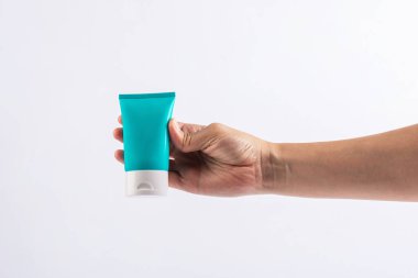 Mavi kozmetik şişesi, cilt bakımı veya beyaz arka planda elde güneş kremi kozmetiği.