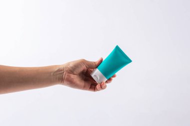 Mavi kozmetik şişesi, cilt bakımı veya beyaz arka planda elde güneş kremi kozmetiği.