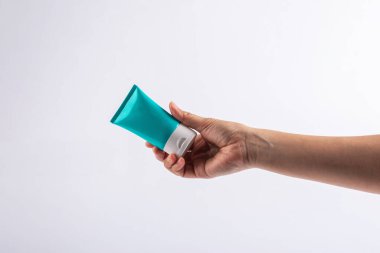 Mavi kozmetik şişesi, cilt bakımı veya beyaz arka planda elde güneş kremi kozmetiği.