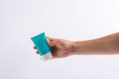 Mavi kozmetik şişesi, cilt bakımı veya beyaz arka planda elde güneş kremi kozmetiği.