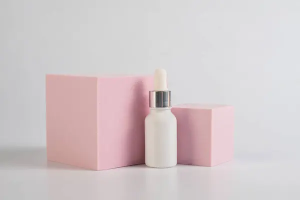 Beyaz cam kozmetik şişesi, cilt bakımı ya da beyaz arka planda şık dekorları olan güneş kremi..