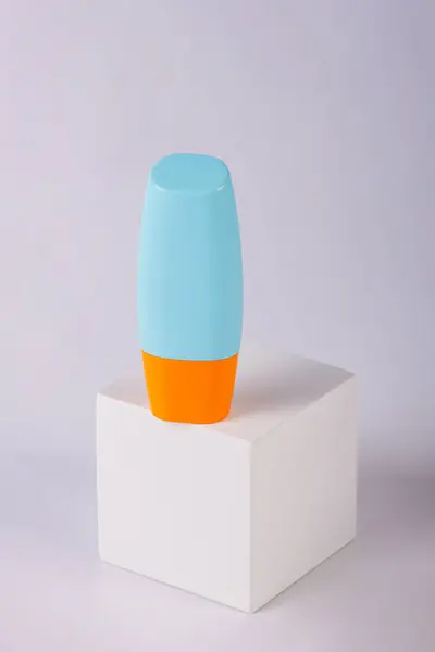 Mavi kozmetik şişesi, cilt bakımı veya beyaz arka planda şık dekorları olan güneş kremi..