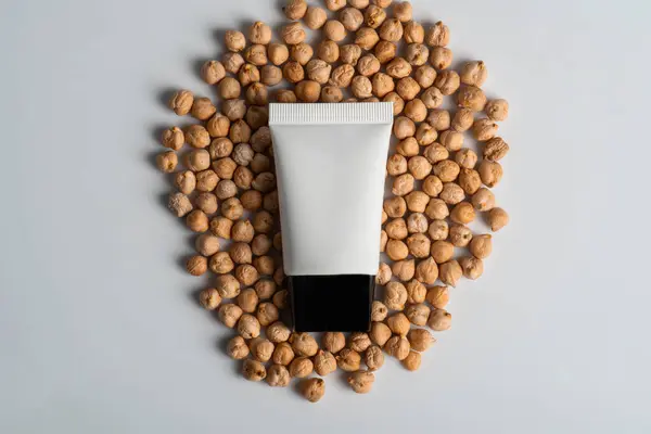 Krem veya losyon için plastik beyaz tüp. Beyaz zemin üzerinde nohut doğal protein kaynağı olan cilt bakımı veya güneş kremi kozmetiği.
