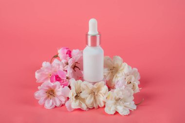Krem veya losyon için plastik beyaz tüp. Cilt bakımı ya da pembe arka planda sahte çiçekli güneş kremi kozmetiği.