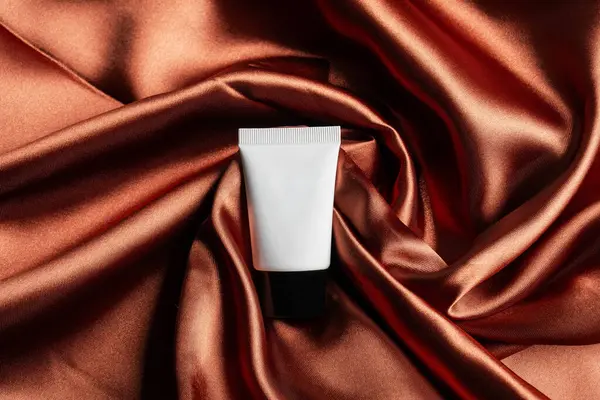 Kozmetik ürünler tüp, şişe, losyon ya da serumda parlak kumaş arka planında