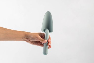 Mavi saplı bahçe araçları ve beyaz arka plan üzerinde el