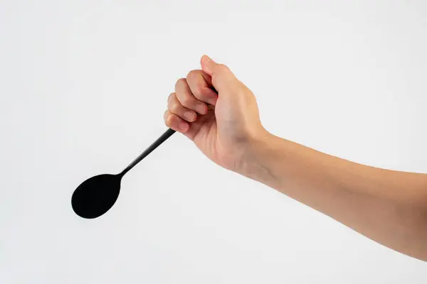 Beyaz arka planda el ve metal kaşık.