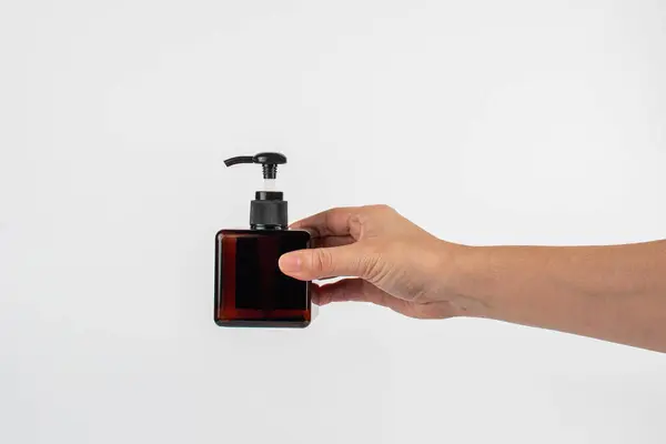 Beyaz arka planda koyu kehribar camından yapılmış kozmetik şişeler.