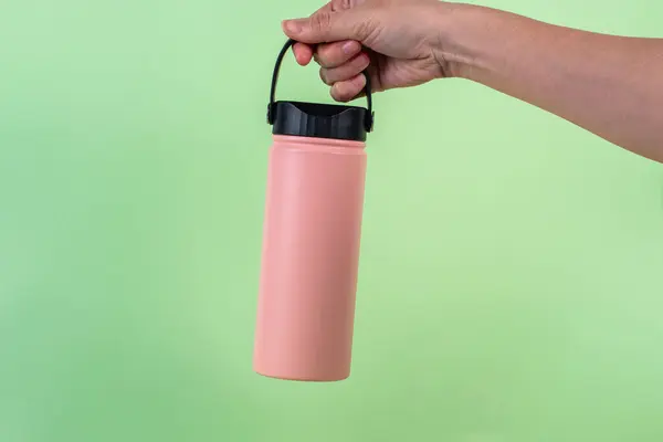 Pembe şişe yuvarlayıcı ve yeşil fırında izole edilmiş el.