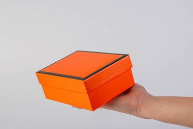 Eldeki turuncu kutu beyaza izole edilmiş.