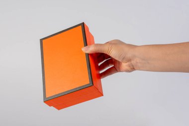 Eldeki turuncu kutu beyaza izole edilmiş.