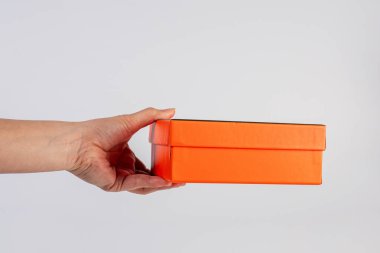 Eldeki turuncu kutu beyaz arkaplanda izole edildi 