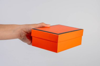 Eldeki turuncu kutu beyaz arkaplanda izole edildi 