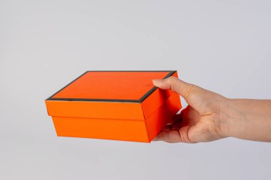 Eldeki turuncu kutu beyaz arkaplanda izole edildi 