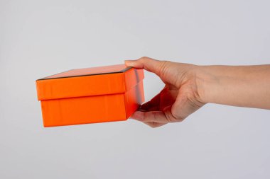 Eldeki turuncu kutu beyaz arkaplanda izole edildi 