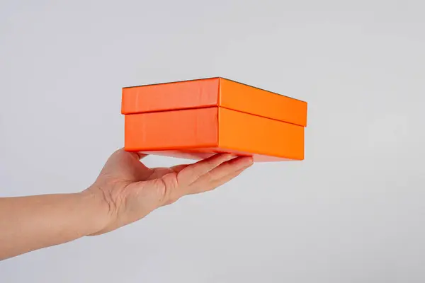 Eldeki turuncu kutu beyaz arkaplanda izole edildi 