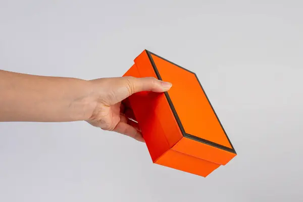 Eldeki turuncu kutu beyaz arkaplanda izole edildi 