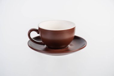 Kahverengi kahve fincanı ve beyaz arka planda kahve tabağı.