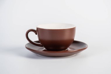 Kahverengi kahve fincanı ve beyaz arka planda kahve tabağı.