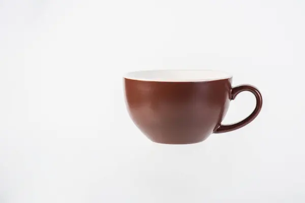 Kahverengi kahve fincanı ve beyaz arka planda kahve tabağı.