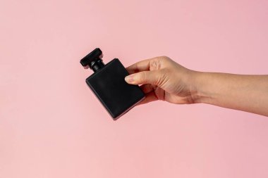 Güzel siyah şişe ve el parfümü, pembe arka planda izole edilmiş..