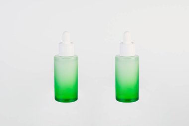 Beyaz arka planda yeşil cam kozmetik şişesi, cilt bakımı veya güneş kremi kozmetiği.