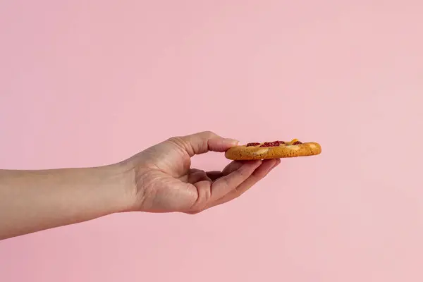 Fındıklı ve çilekli vanilyalı kurabiye ve pembe arka planda el.