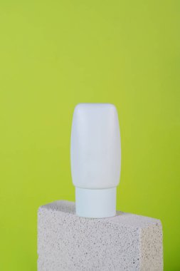 Krem veya losyon için plastik beyaz tüp. Yeşil arka planda şık dekorları olan cilt bakımı veya güneş kremi kozmetiği.