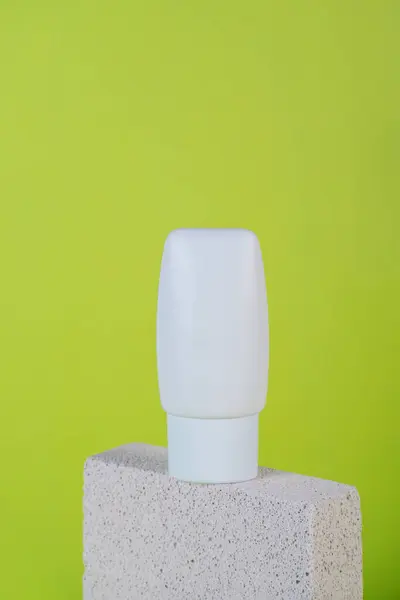 Krem veya losyon için plastik beyaz tüp. Yeşil arka planda şık dekorları olan cilt bakımı veya güneş kremi kozmetiği.