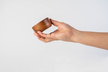 Beyaz arka planda küçük yuvarlak tahta bardak.