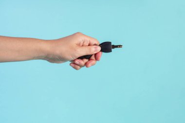Black locker key in hand on blue background