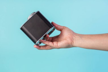 Black can for packaging in hand on blue background.