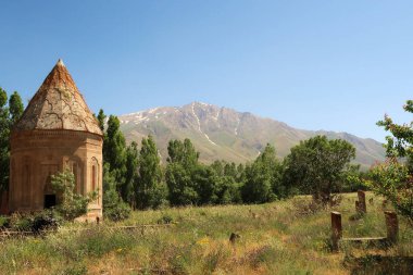 Halime Hatun 'un mezarı, mezarı, anıt mezar, Halime Hatun Kumbeti, arka planda Artos Dağı karla kaplı ve yanında Van, Van Golu Gölü, Gevas, Türkiye 2022 yakınlarında birkaç mezar taşı bulunuyor.