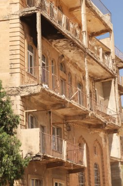 Türkiye 'nin eski Mardin kentindeki bir apartman binasının birçok balkonuyla geleneksel cepheyi ayrıntılı bir şekilde anlat, 2022