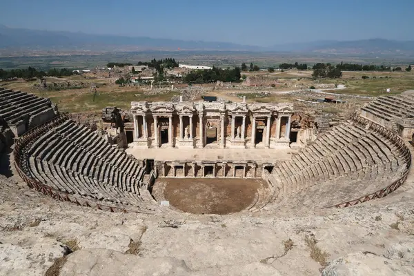 Arka planda Pamukkale, Denizli, Türkiye 2022 'de yer alan Hierapolis arkeoloji sahasındaki Amfitiyatro Tiyatrosu.