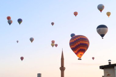 Sıcak hava balonları sabahın erken saatlerinde Goreme kasabasında hemen yanında bir minare kulesi olan Goreme, Kapadokya, Türkiye 2022