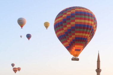 Sıcak hava balonları sabahın erken saatlerinde Goreme kasabasında hemen yanında bir minare kulesi olan Goreme, Kapadokya, Türkiye 2022