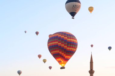 Sıcak hava balonları sabahın erken saatlerinde Goreme kasabasında hemen yanında bir minare kulesi olan Goreme, Kapadokya, Türkiye 2022